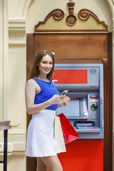 Happy brunette woman withdrawing money from credit card at ATM