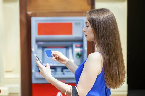 Happy brunette woman withdrawing money from credit card at ATM