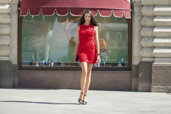 Young woman in red dress walking in the shop