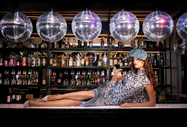 Sexy young woman lying on the bar at a night disco club