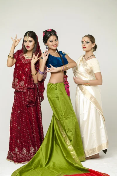 Three young women in indian dress on gray background