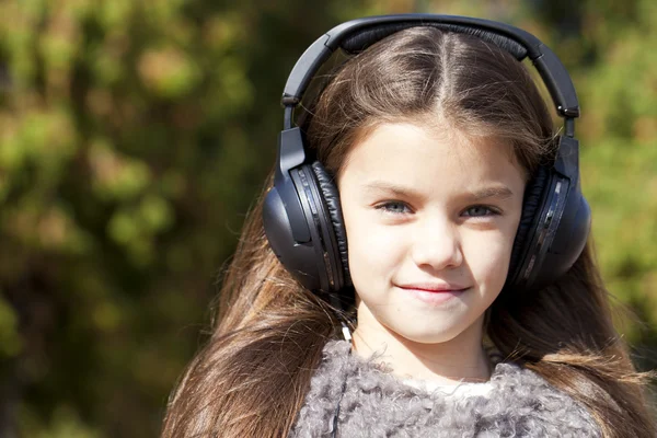 Beautiful little girl listening to music on headphones