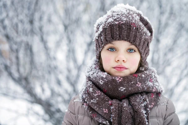 Happy little girl on the background of a winter park