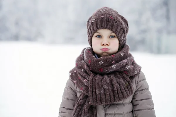 Happy little girl on the background of a winter park