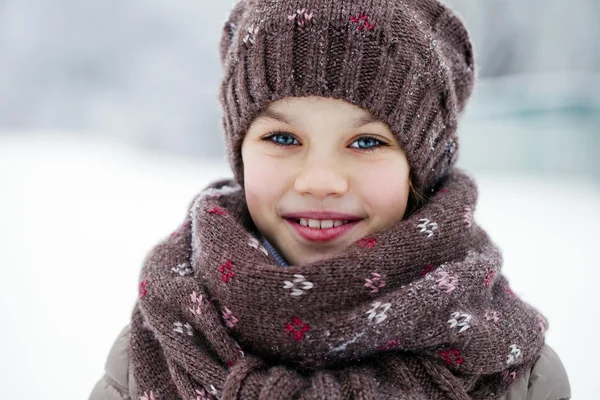 Happy little girl on the background of a winter park