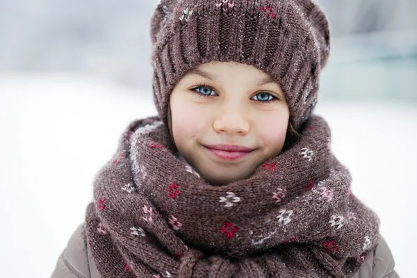 Happy little girl on the background of a winter park