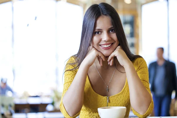 Beautiful young woman sitting in a coffee shop and drink tea
