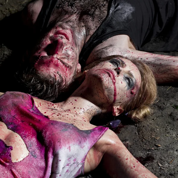 A couple of bloody man and woman lying on the ground