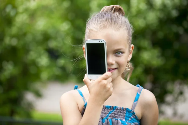 Happy little girl covers her face screen smartphone
