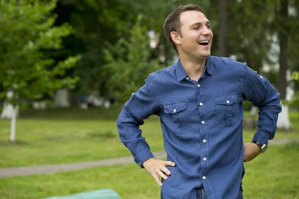 Young handsome man in a blue shirt on the background of summer p