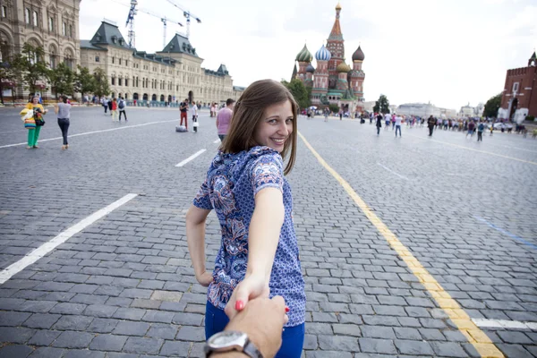 Young happy girl pulls the guys hand on the Red Square in Moscow