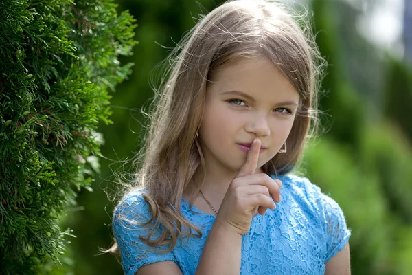 Little girl has put forefinger to lips as sign of silence