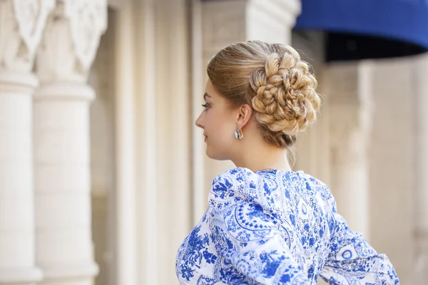 Portrait of young blonde woman in blue dress