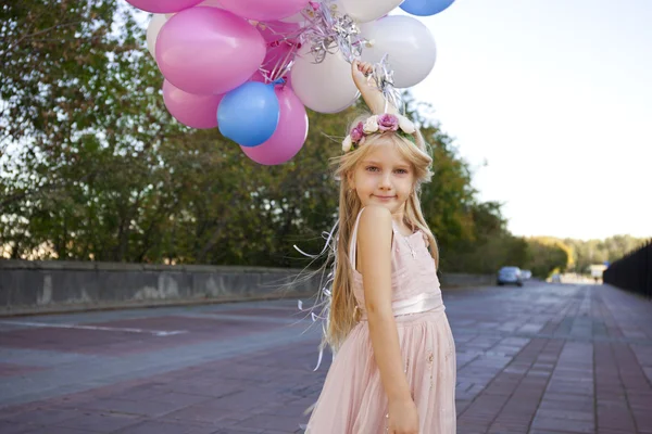 Little five-year girl in a pink dress holding balloons