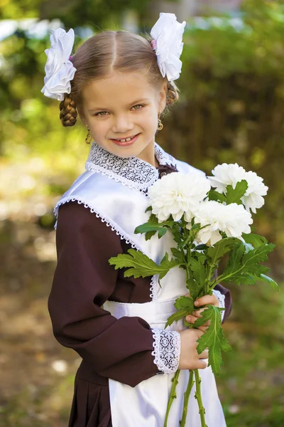 Portrait of a beautiful young first-grader in a festive school u