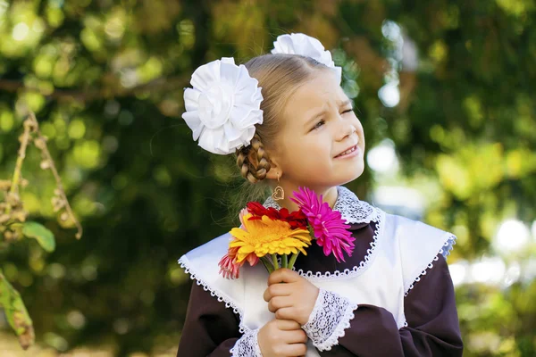 Portrait of a beautiful young first-grader in a festive school u