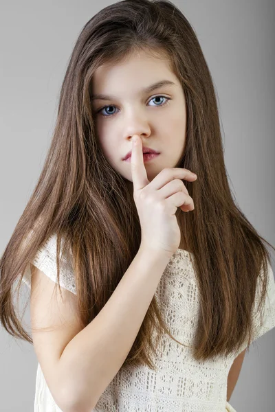 Little girl has put forefinger to lips as sign of silence