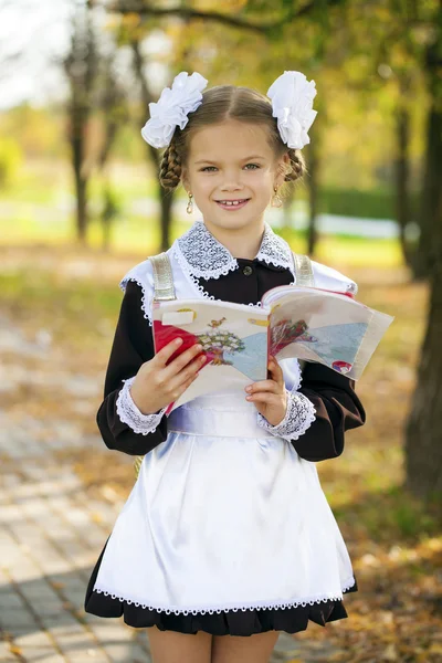 Happy little schoolgirl in autumn park