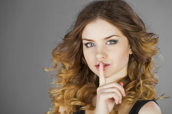 Woman has put forefinger to lips as sign of silence
