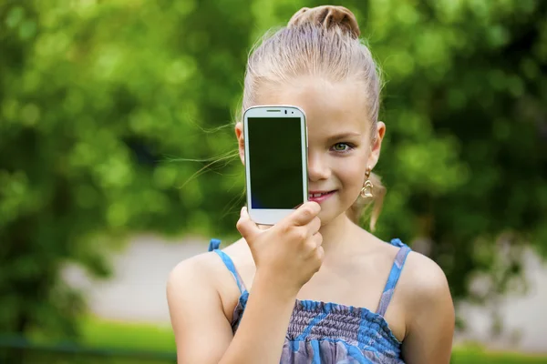 Happy little girl covers her face screen smartphone