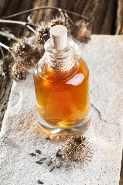 Bottle with burdock oil and dry flowers