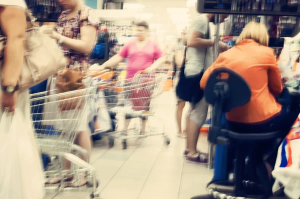 Customers and shopping carts in supermarket