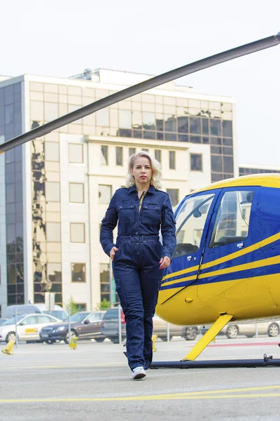 Pretty pilot woman on helicopter background