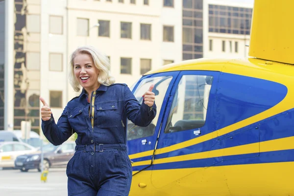 Pretty pilot woman on helicopter background