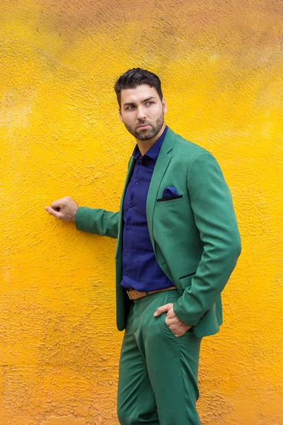 Man in gren suit on yellow wall background.