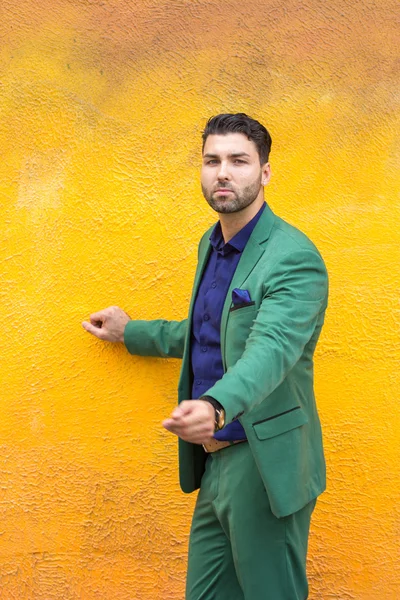 Man in gren suit on yellow wall background.
