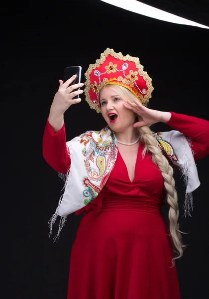 Girl standing in Russian traditional costume with mobile phone