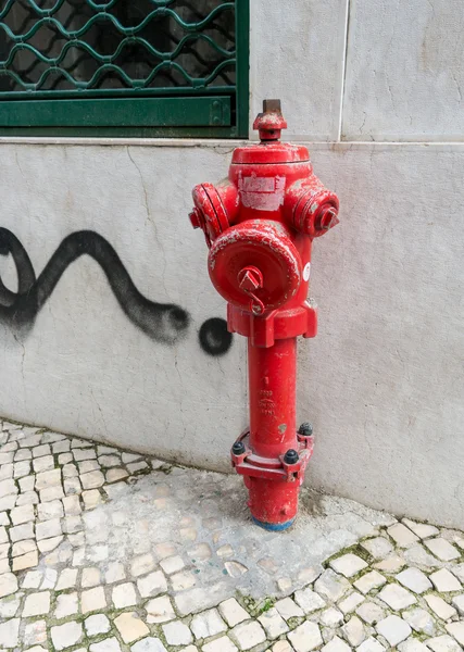 Weathered red fire hydrant near a cement wall