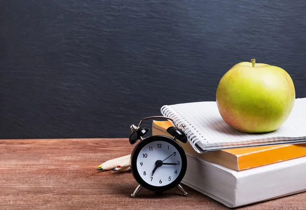 Books, clock and apple on the table