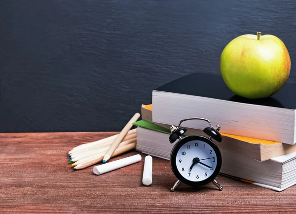 Books, apple and clock on the table