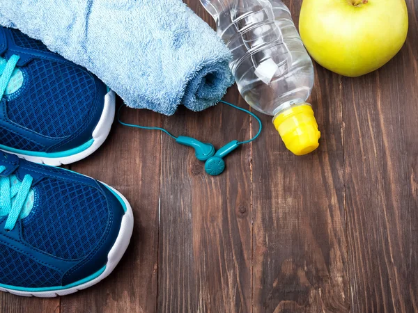 Sneakers, water, towel and earphones on the wooden background