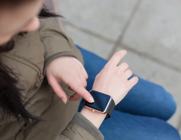 Hands of a girl using her smart watch outdoors