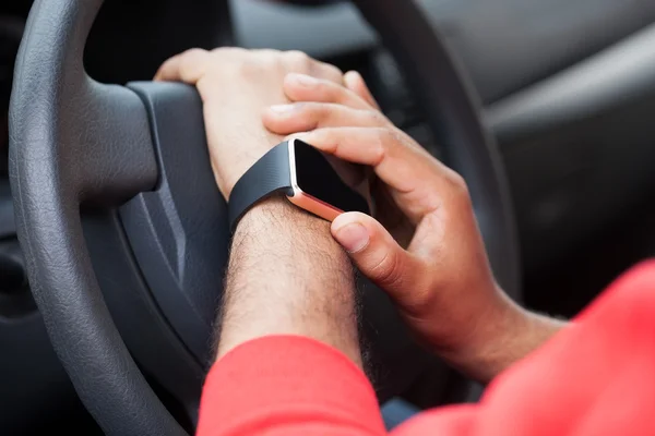 Hands of African man using smart watch sitting in a car