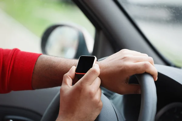 Hands of black man with smart wrist watch in car
