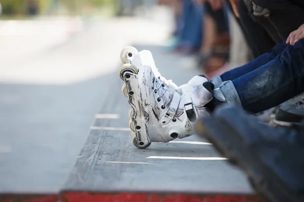 Aggressive inline rollerblader sitting in outdoor skate park