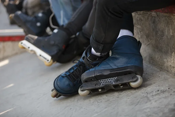Aggressive inline rollerblader sitting in outdoor skate park