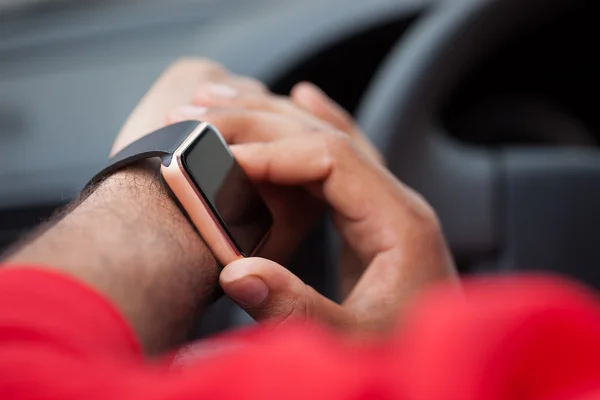 Hands of African man using smart watch sitting in a car