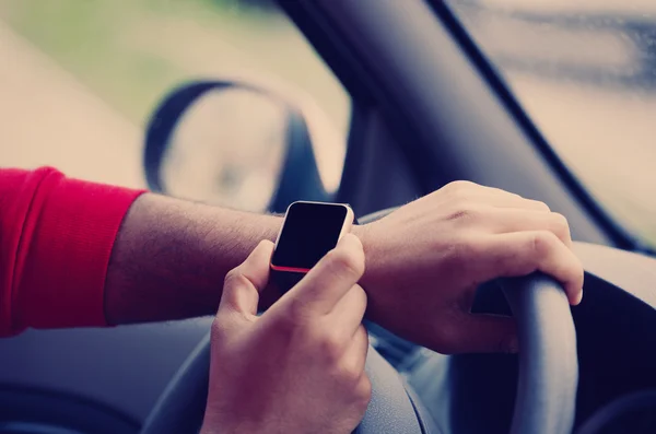 Hands of black man with smart wrist watch in car