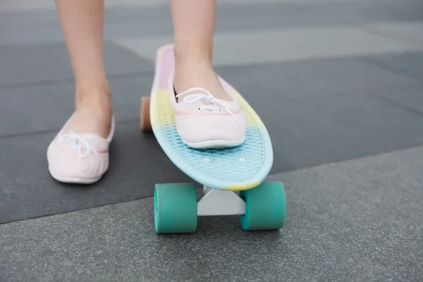 Feet of girl riding colorful short cruiser skateboard