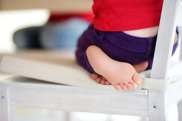 Cute little feet of a child sitting on a chair