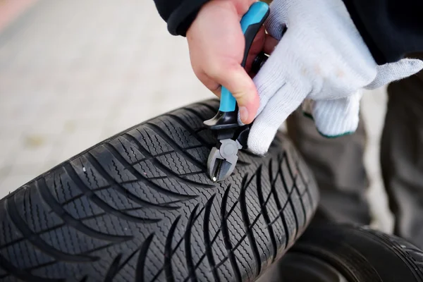 Hand Pulling nail out of tire