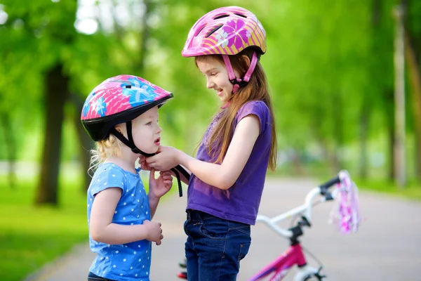 Girl helping her sister to put a helmet