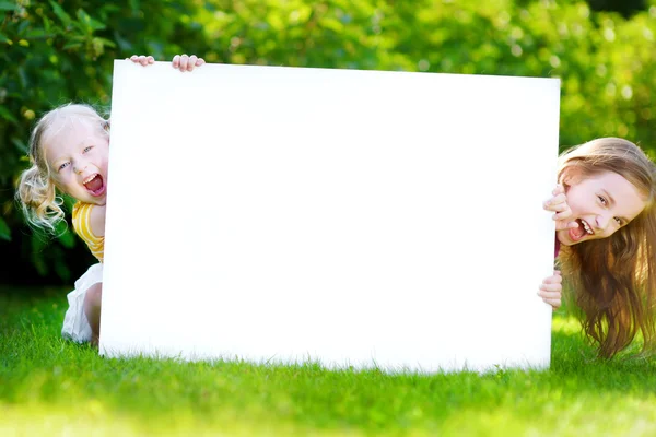 Sisters holding blank whiteboard