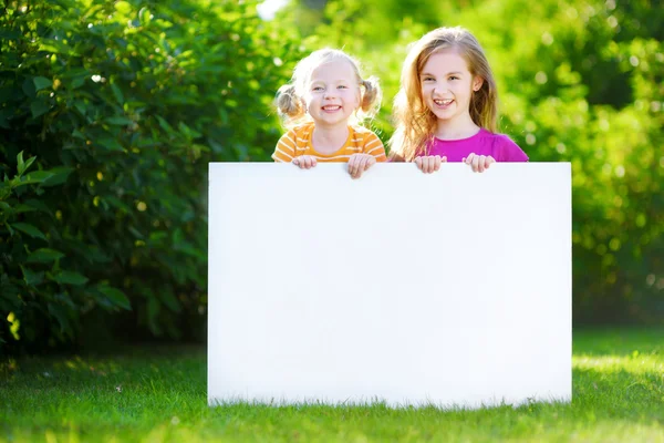 Sisters holding blank whiteboard