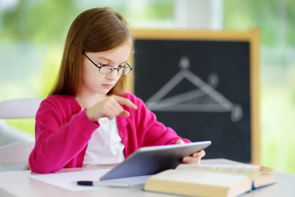 Smart little schoolgirl with digital tablet