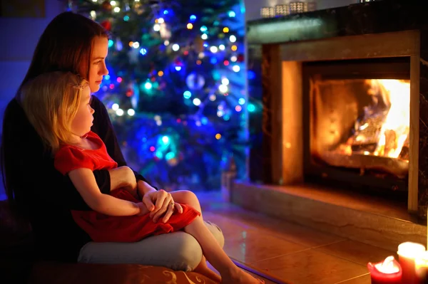 Mother and daughter sitting by a fireplace on Christmas